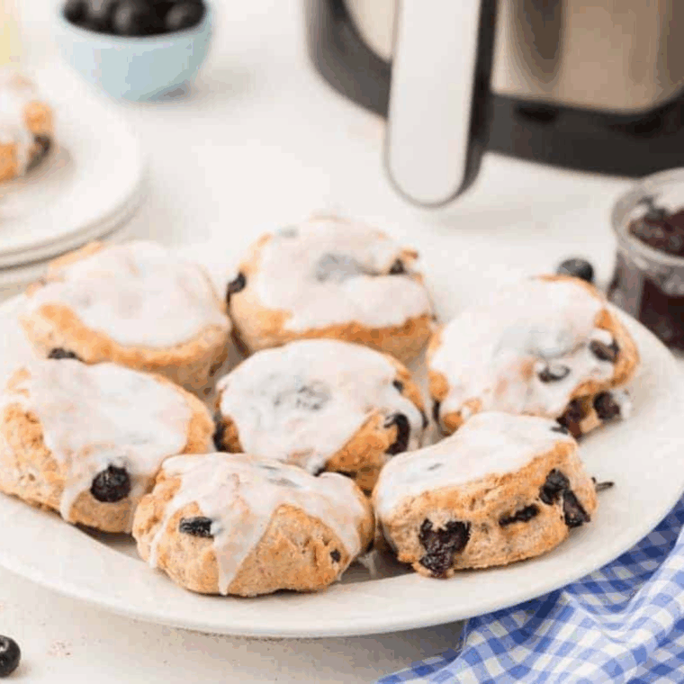 Freshly baked air fryer blueberry biscuits, golden brown with juicy blueberries peeking through.