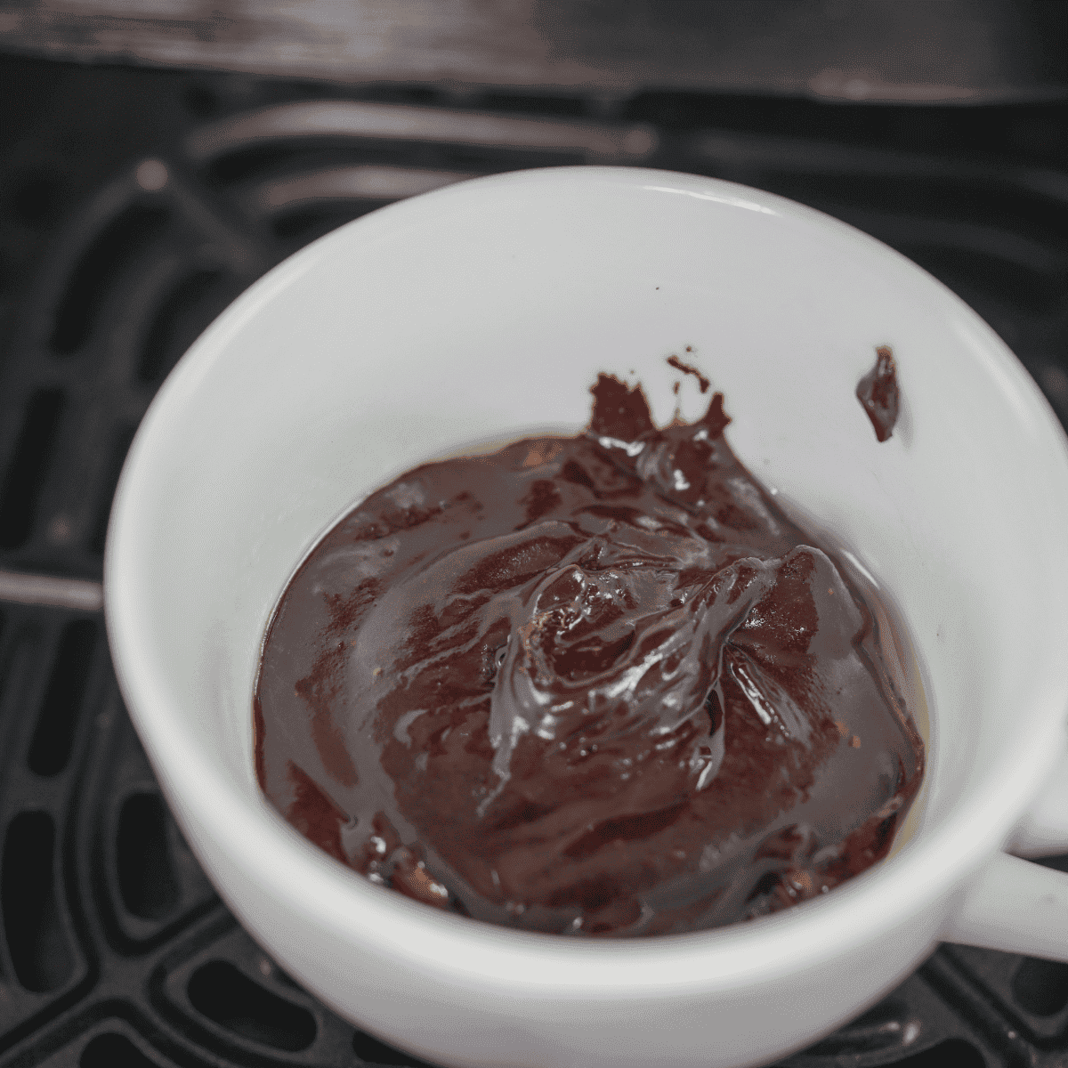 Mug brownie cooking in air fryer at 330°F for 5 to 7 minutes until set and fudgy in the center