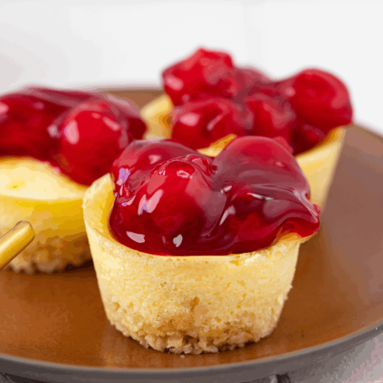 Air fryer mini cheesecakes with golden crust and creamy filling, topped with fruit.