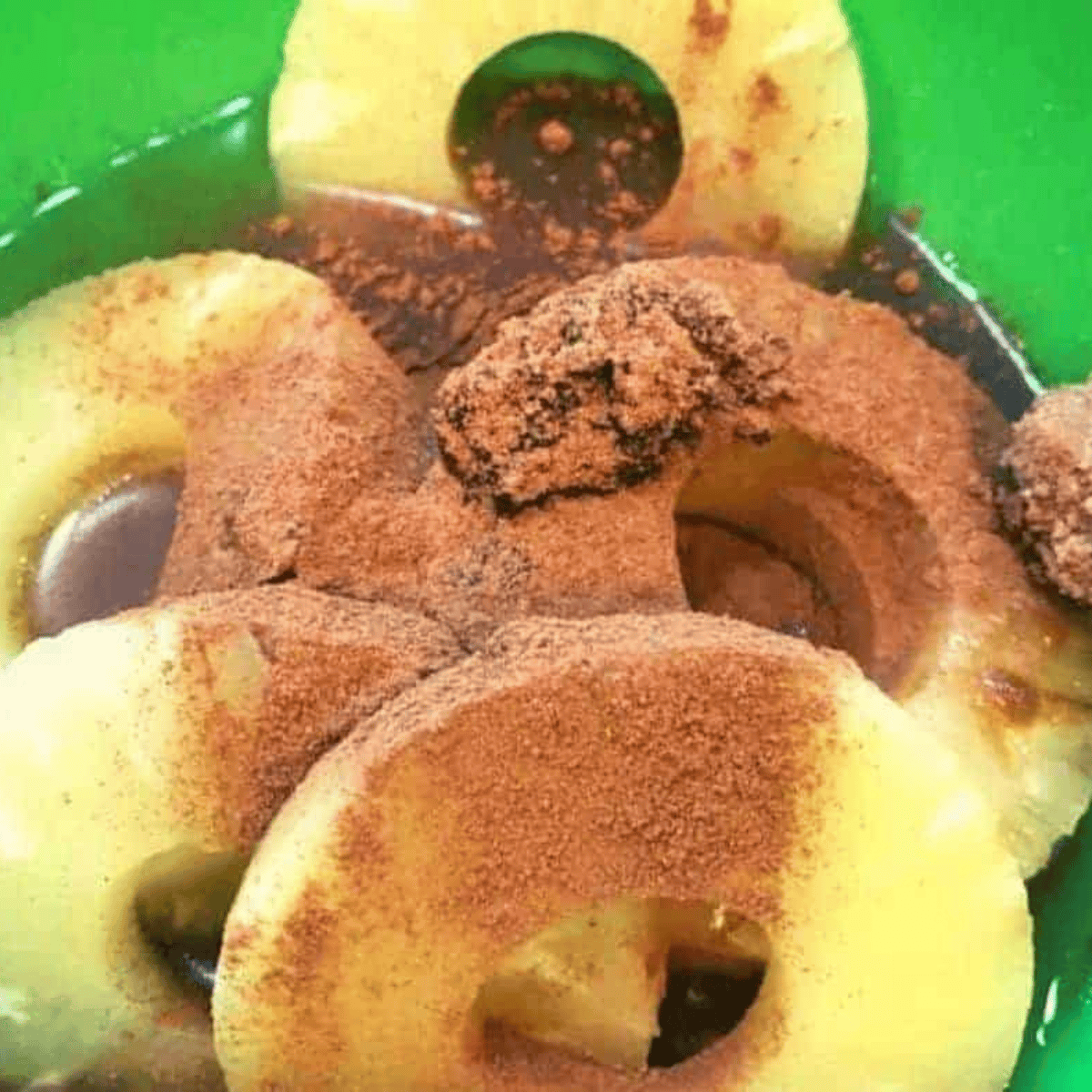 Bowl of pineapple slices soaking in rum and spices, ready to chill.