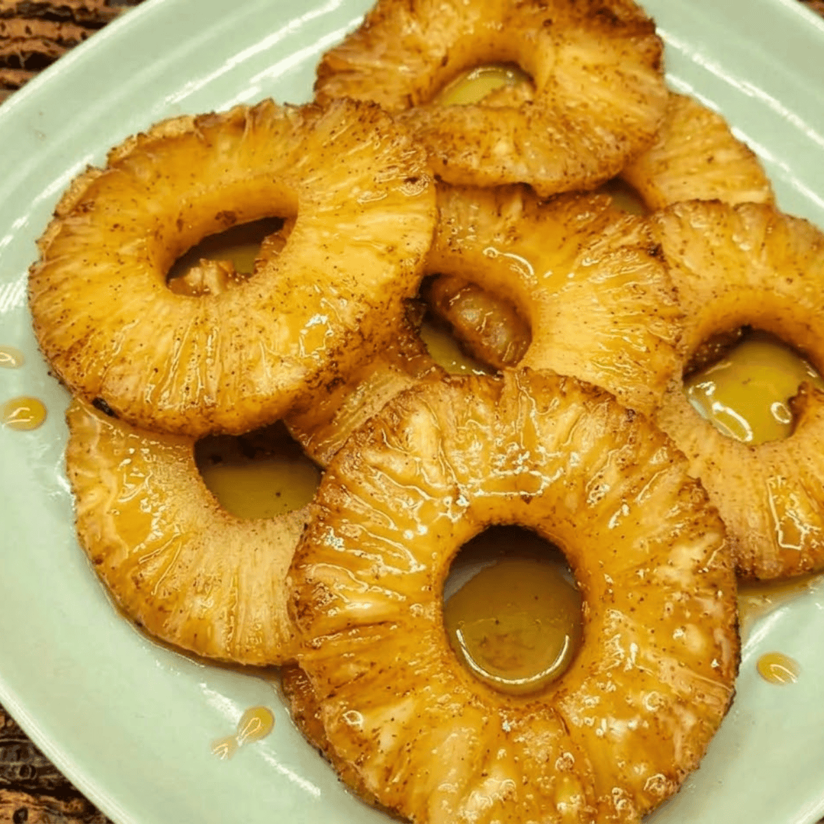 Air Fryer Rum Soaked Pineapple caramelized slices in a white bowl, garnished with mint.
