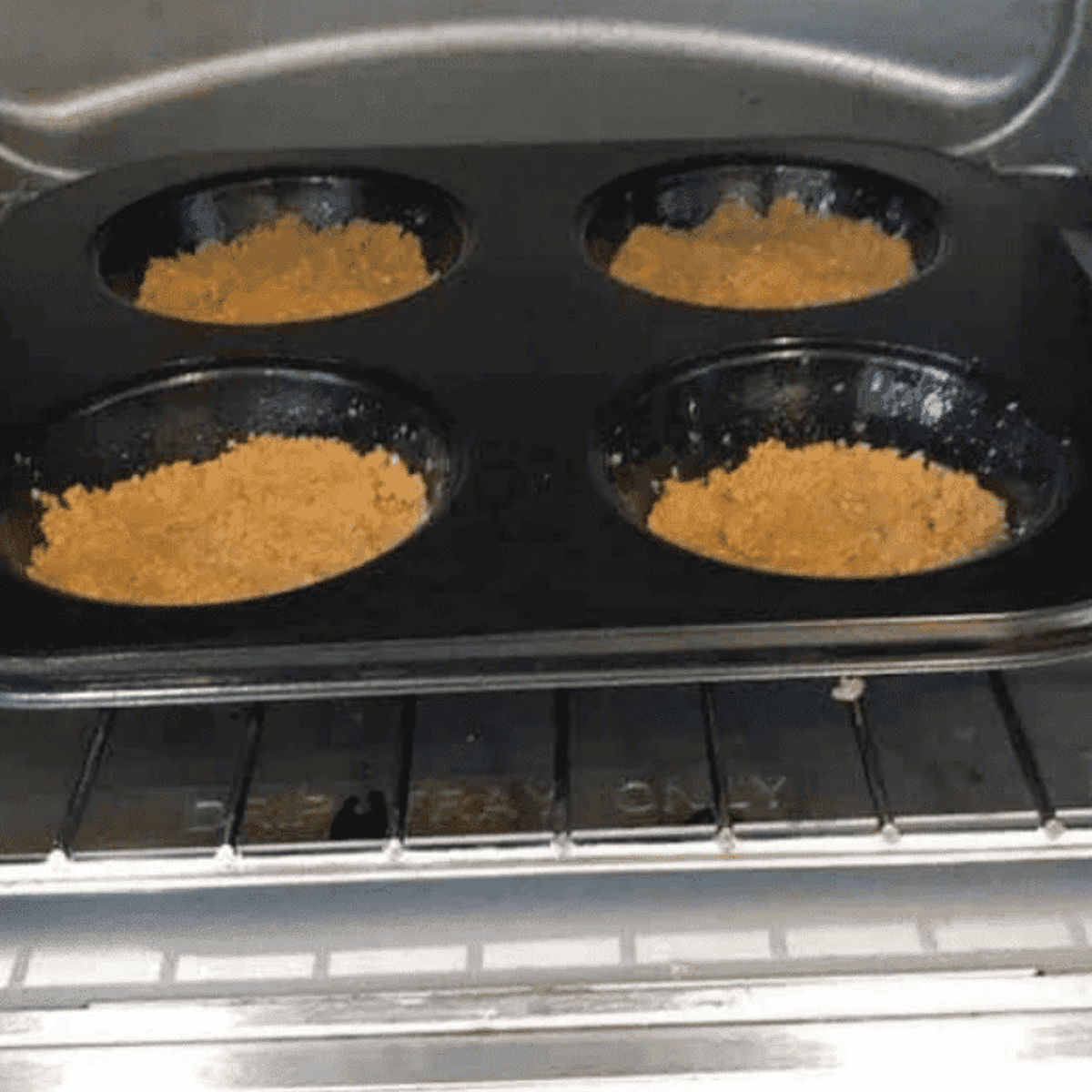Graham cracker crusts baking in an air fryer, edges turning golden brown.