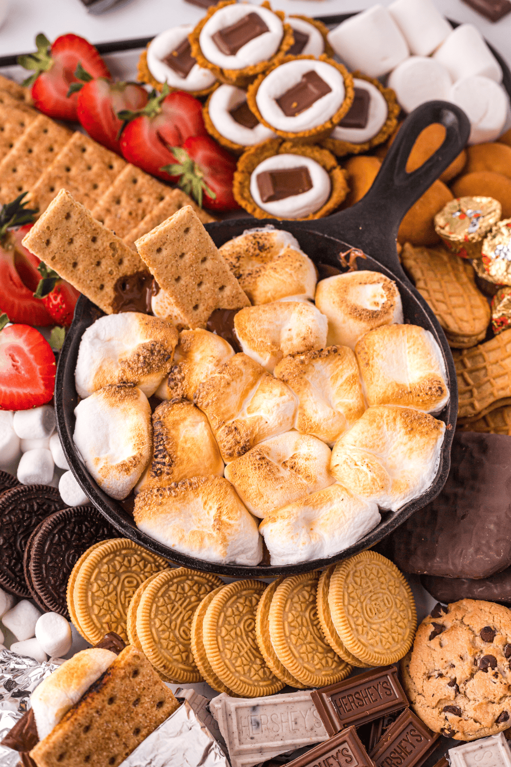 Chocolate squares pressed into toasted marshmallows in cookie cups, cooling on a tray.