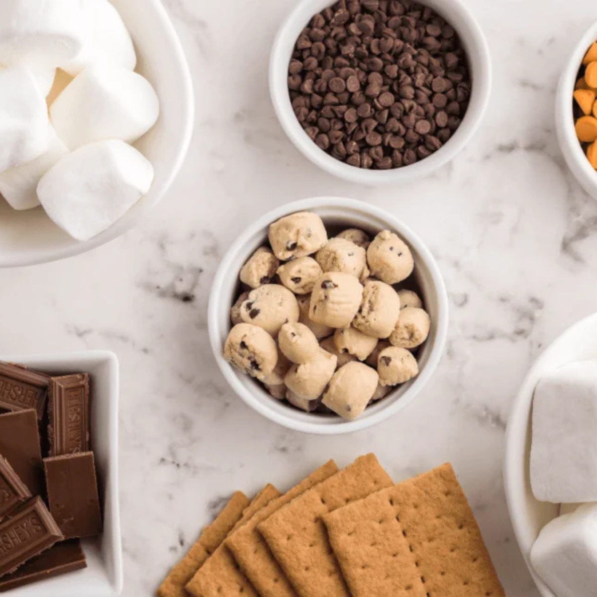 overhead flat lay of ingredients. Alt text: "chocolate chips, marshmallows, and graham crackers laid out for air fryer s'mores dip