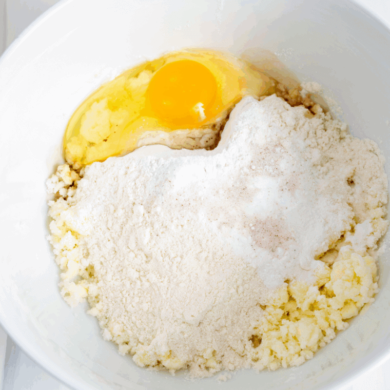 Creaming butter, sugar, salt, vanilla, egg yolks, flour, and milk in a mixing bowl