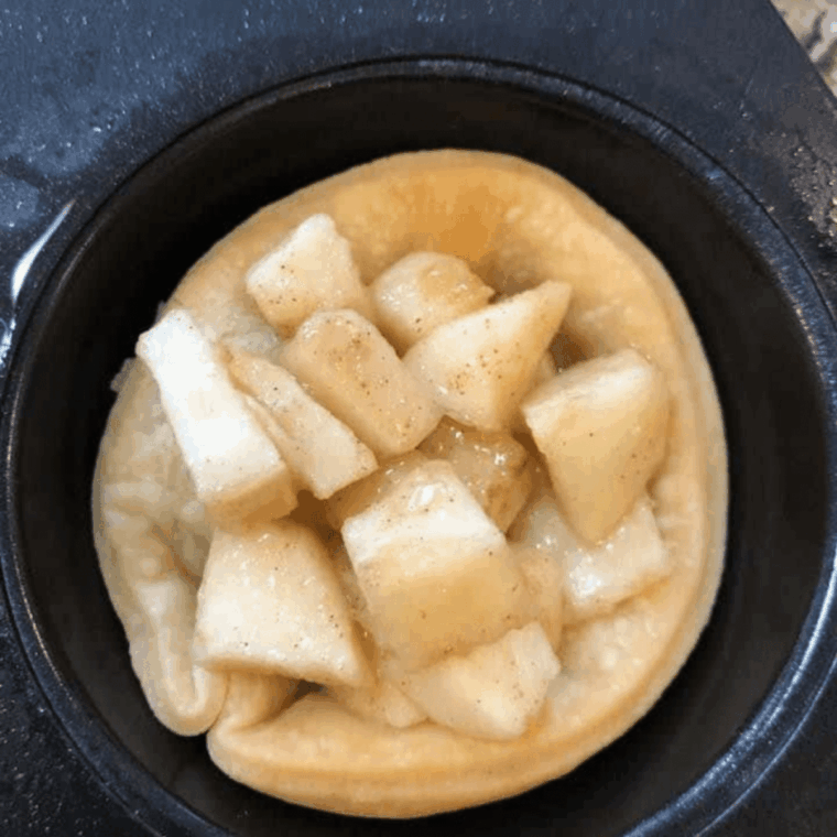 Mini muffin tin apple pies filled with pie filling, topped with lattice dough, brushed with butter, sprinkled with sugar, and air frying at 320°F.