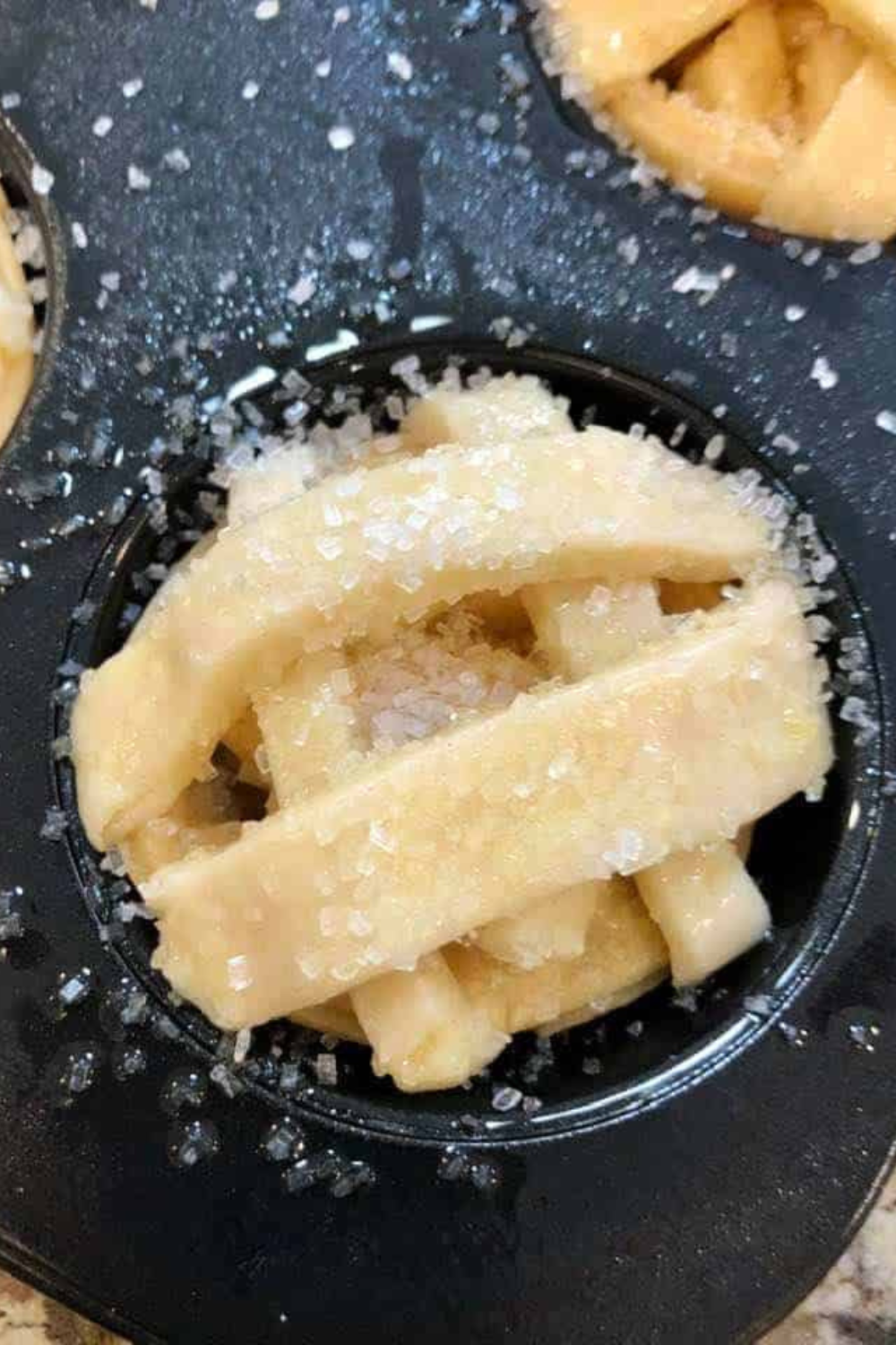Golden mini apple pies in an air fryer muffin tin with cinnamon apple filling