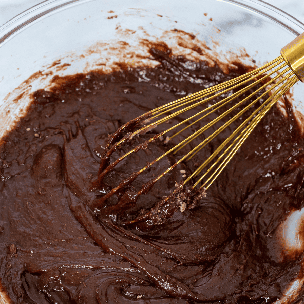 Melting butter, sugar, and cocoa powder in a microwave-safe bowl in 30-second intervals, stirring until smooth chocolate mixture forms.