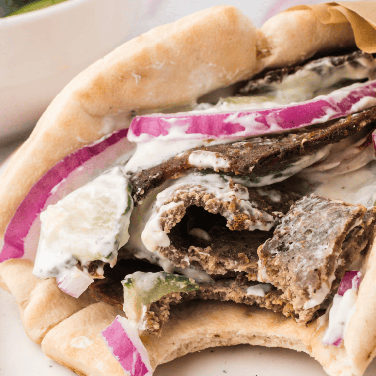 Air fryer beef gyro wrapped in warm pita with garlic sauce and fresh toppings.