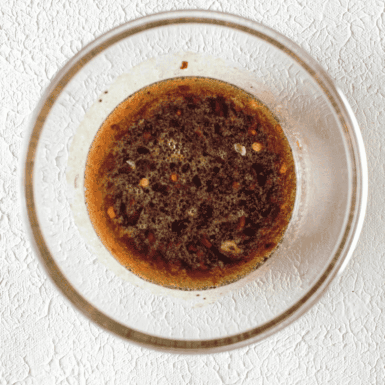 Honey garlic sauce being whisked in a bowl with melted butter, garlic, soy sauce, and lime juice