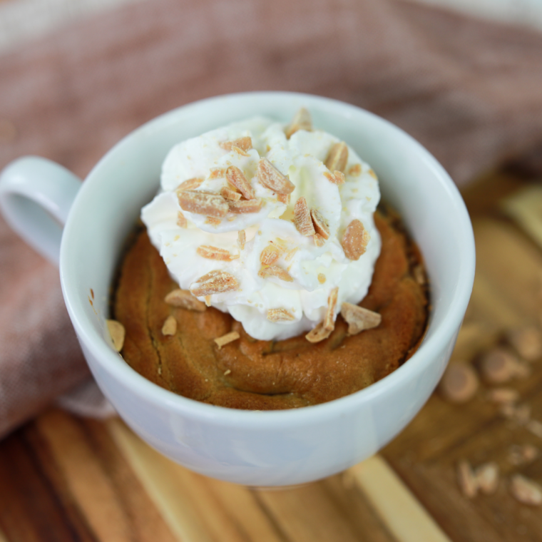 Close up of a soft peanut butter mug cake made in the air fryer, drizzled with melted peanut butter