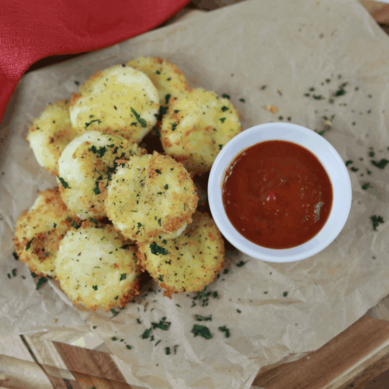 Crispy breaded air fryer Babybel cheese bites served on a white plate with warm marinara sauce