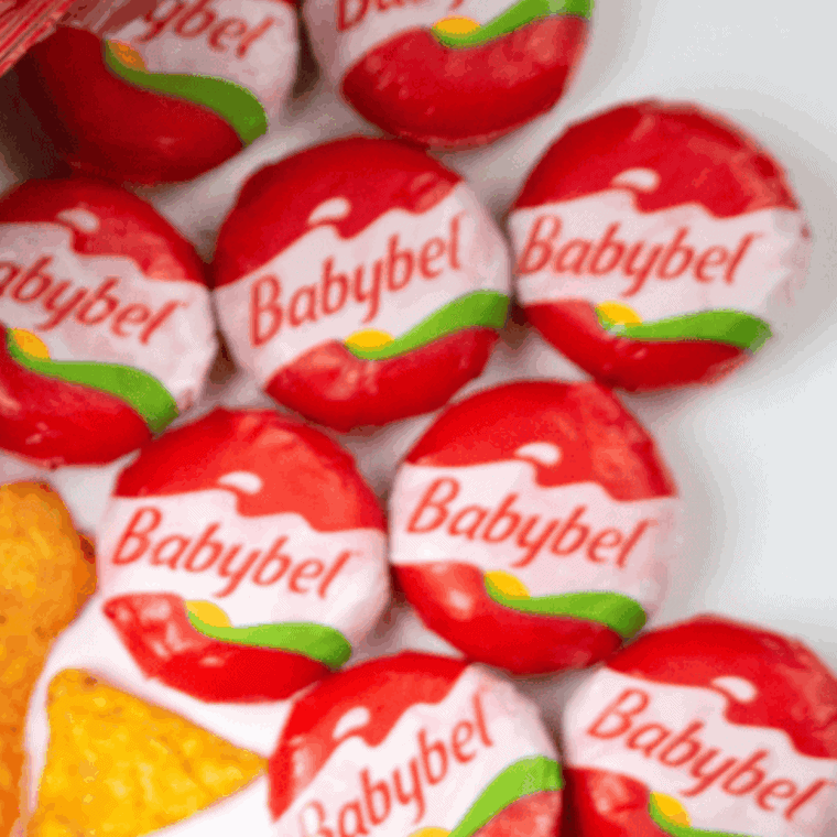 Ingredients for air fryer Babybel cheese including flour, eggs, panko breadcrumbs, Parmesan, and Babybel rounds on a kitchen counter.
