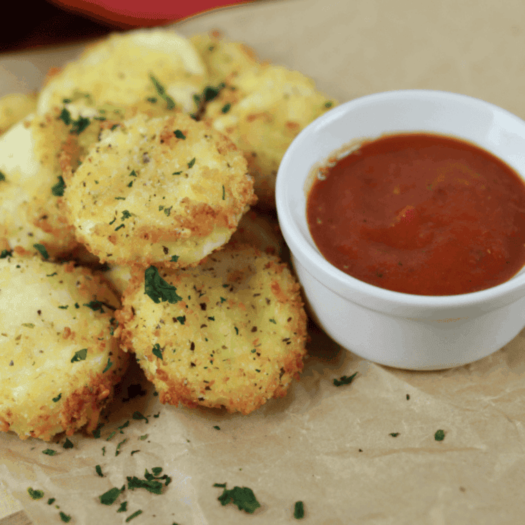 Golden crispy air fryer Babybel cheese bites stacked on a white plate with marinara dipping sauce