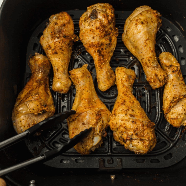 Cooked Cajun chicken drumsticks in the air fryer basket.