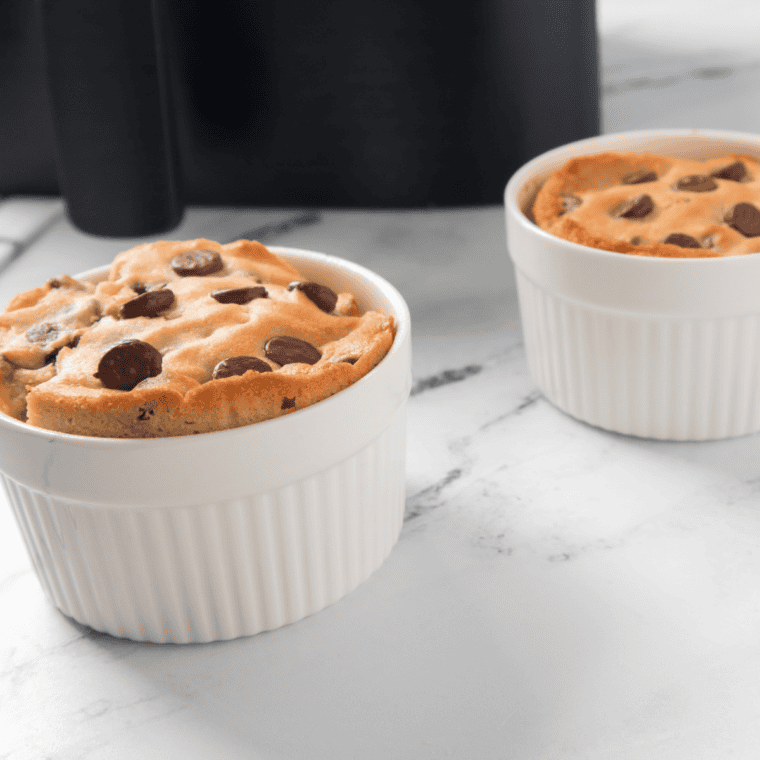 Air fryer chocolate chip cookie in a cup served warm in a ramekin with melted chocolate chips on top and a soft, gooey center.