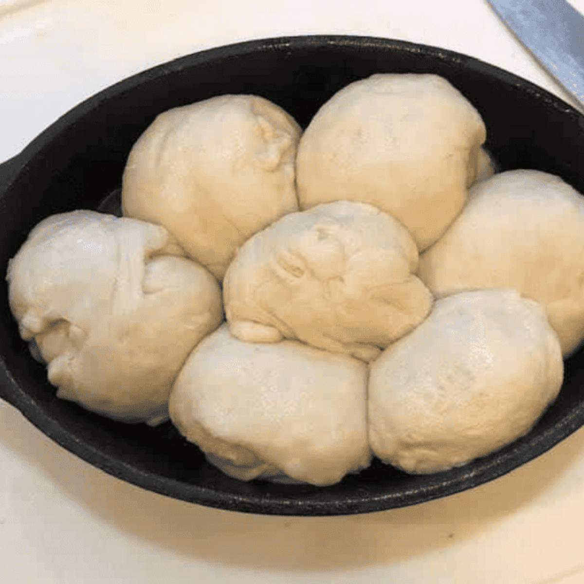 Buttered biscuit dough in pan topped with garlic butter and Parmesan
