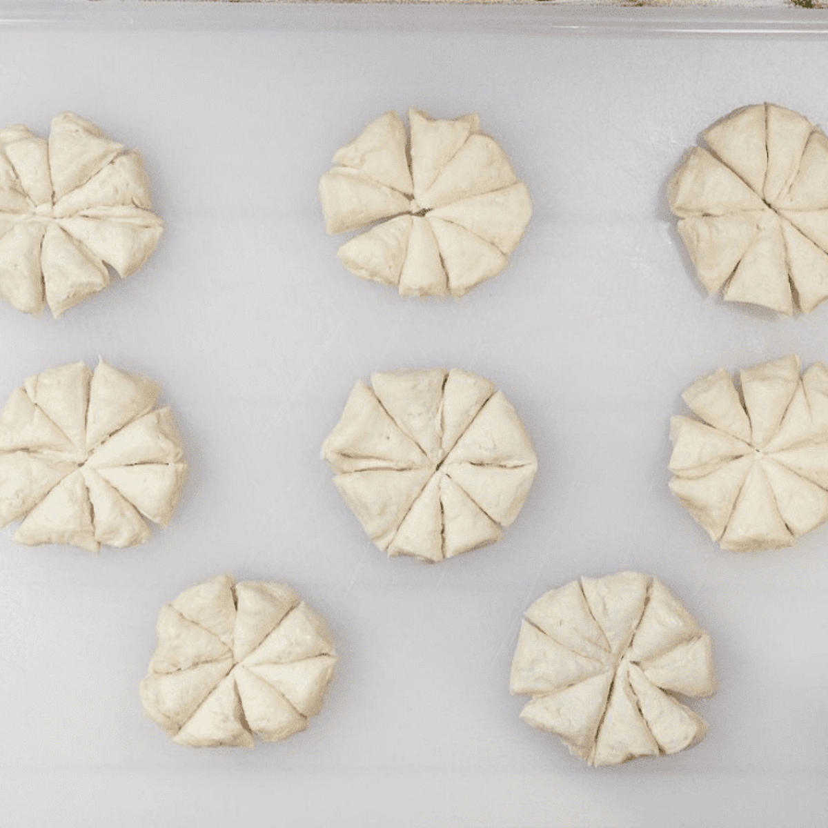 Cutting biscuit dough into small, one-inch pieces for pizza bread.