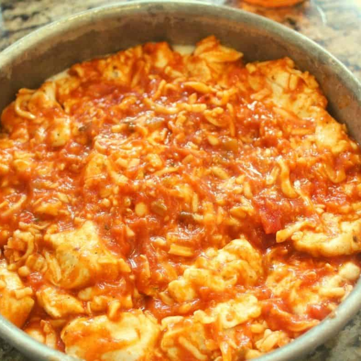 Mixing biscuit dough with pizza sauce, cheese, pepperoni, and seasonings in a bowl before air frying.