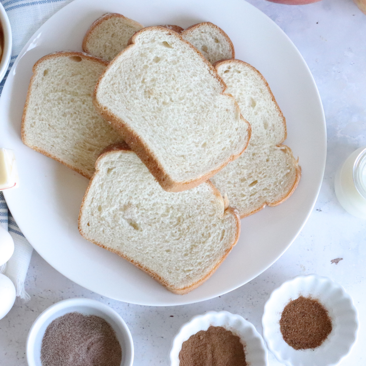 Ingredients for air fryer pumpkin French toast laid out: brioche slices, eggs, pumpkin puree, milk, brown sugar and spices