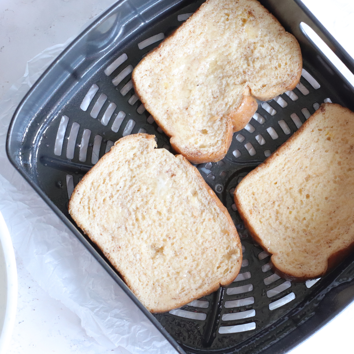 Soaked pumpkin French toast slices arranged in a single layer in an air fryer basket