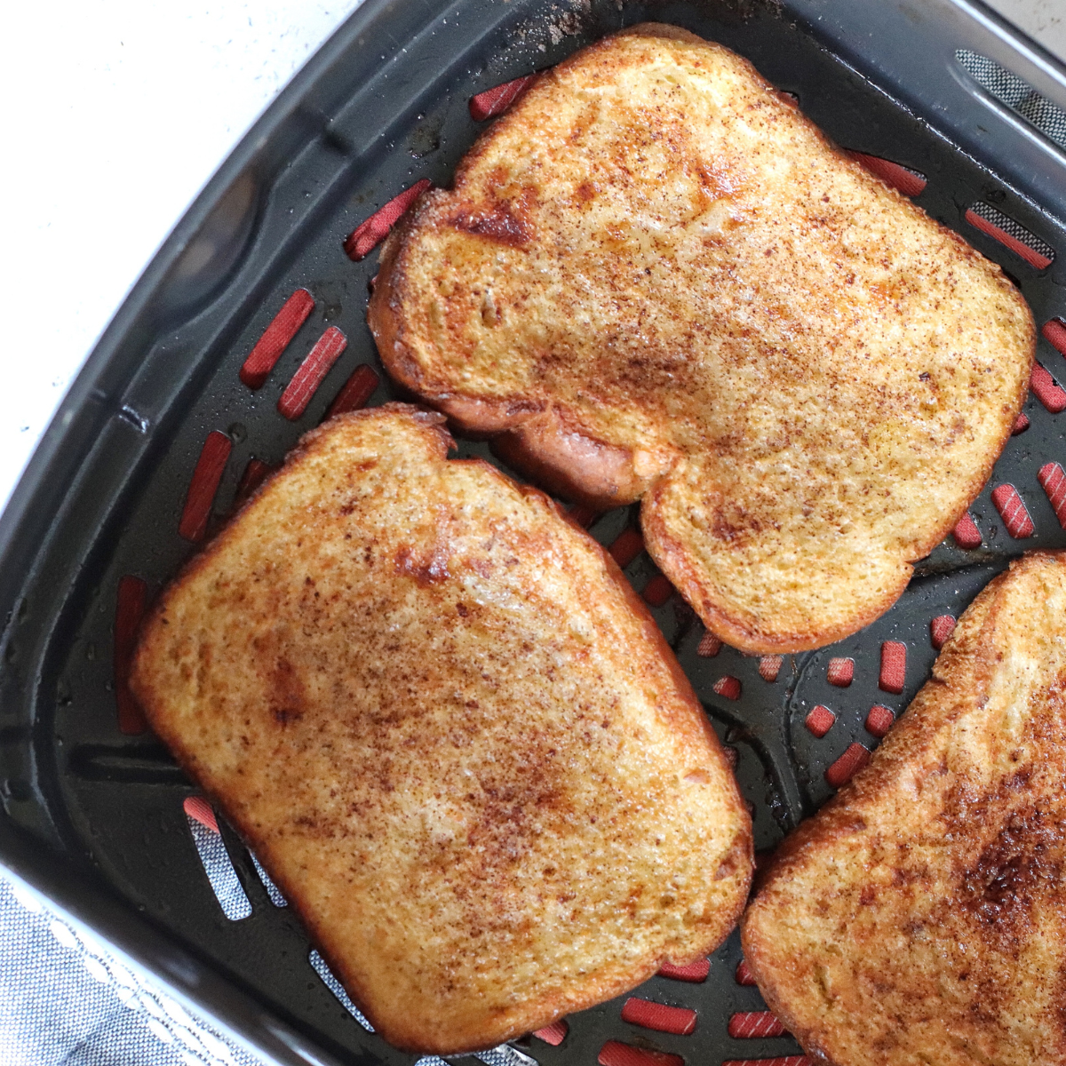 Finished pumpkin French toast in the air fryer basket, golden brown and crisp at the edges