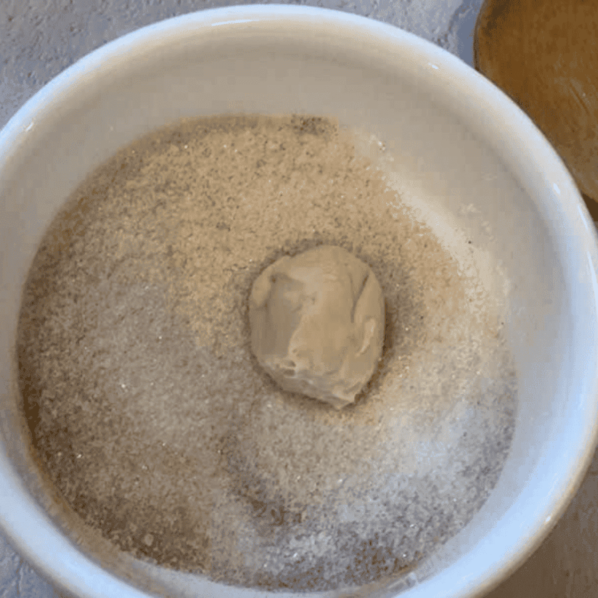 Small bowls with cinnamon sugar and melted butter mixture, rolling dough into balls
