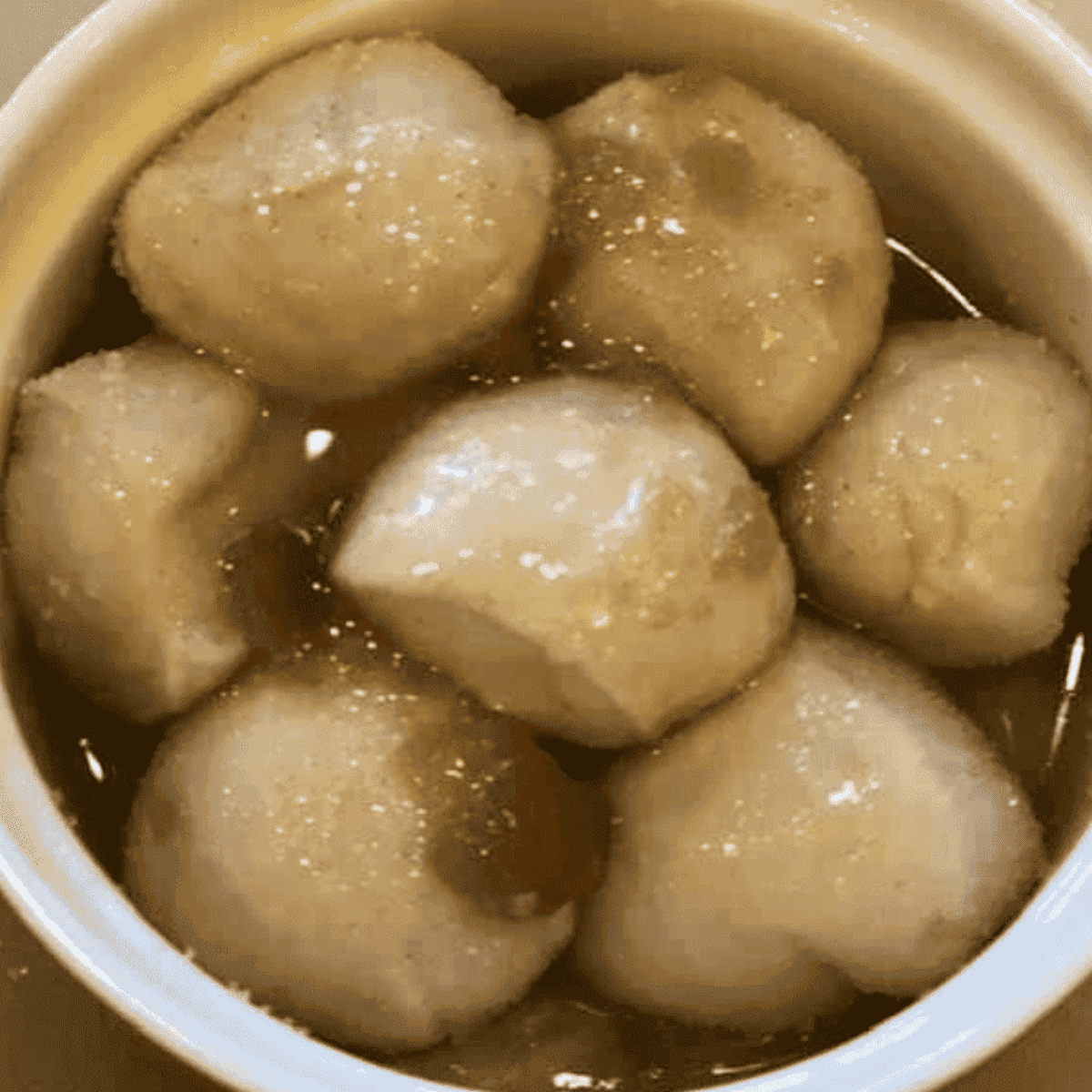 Dough balls coated in cinnamon sugar and layered in greased ramekin with melted butter drizzled on top