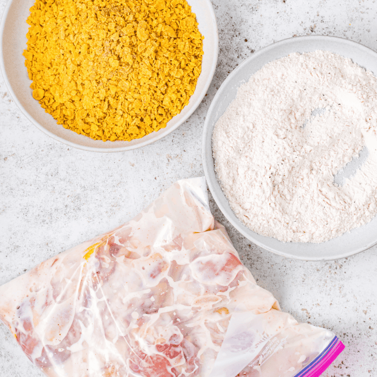 Three-bowl breading station with seasoned flour, egg wash, and cereal crumbs for Captain Crunch Chicken