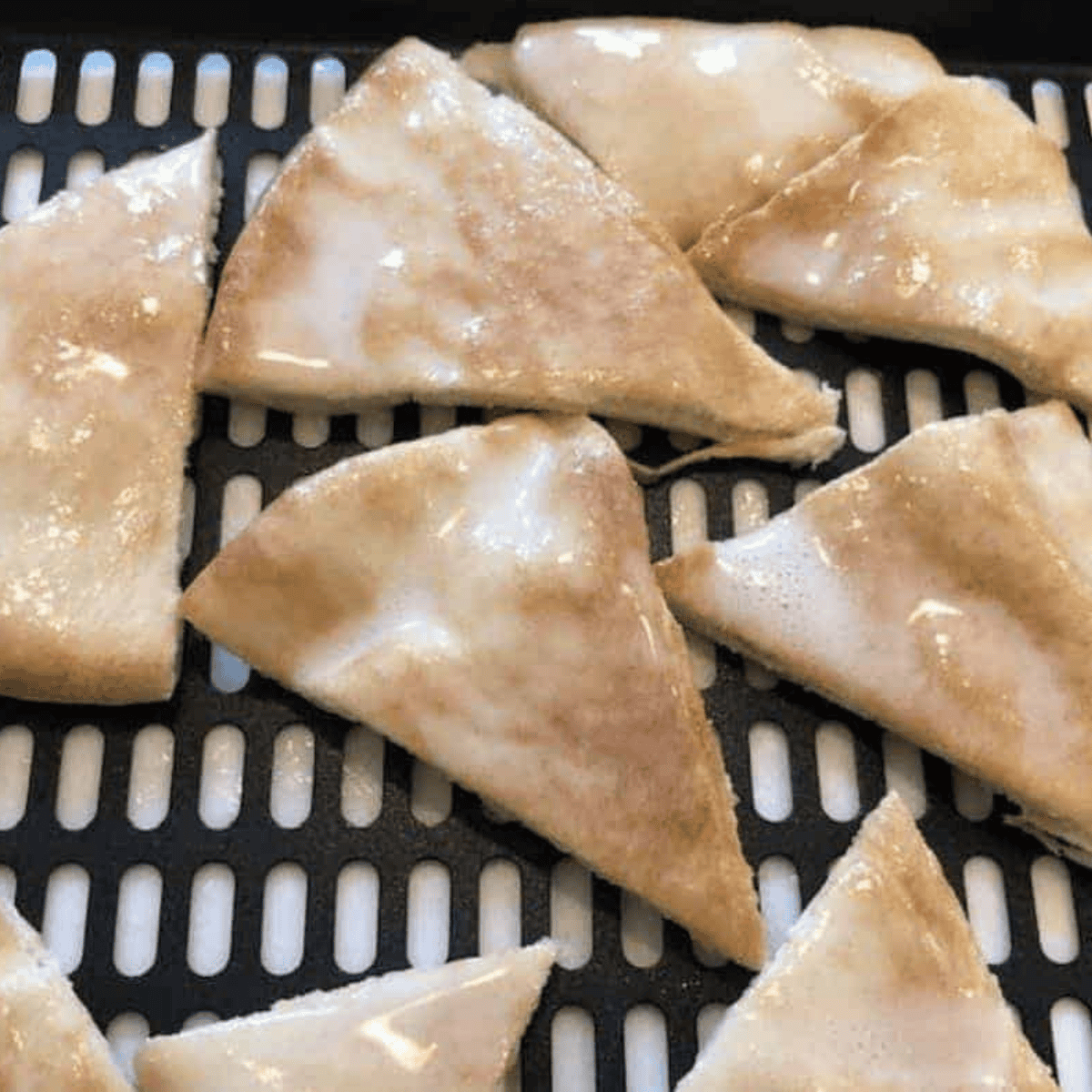 Pita chips being tossed with olive oil and spices then arranged in a single layer on baking sheet for baking or air fryer cooking