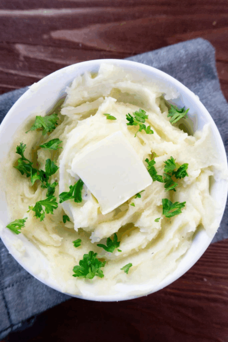 Creamy, golden truffle mashed potatoes garnished with fresh herbs, served in a bowl