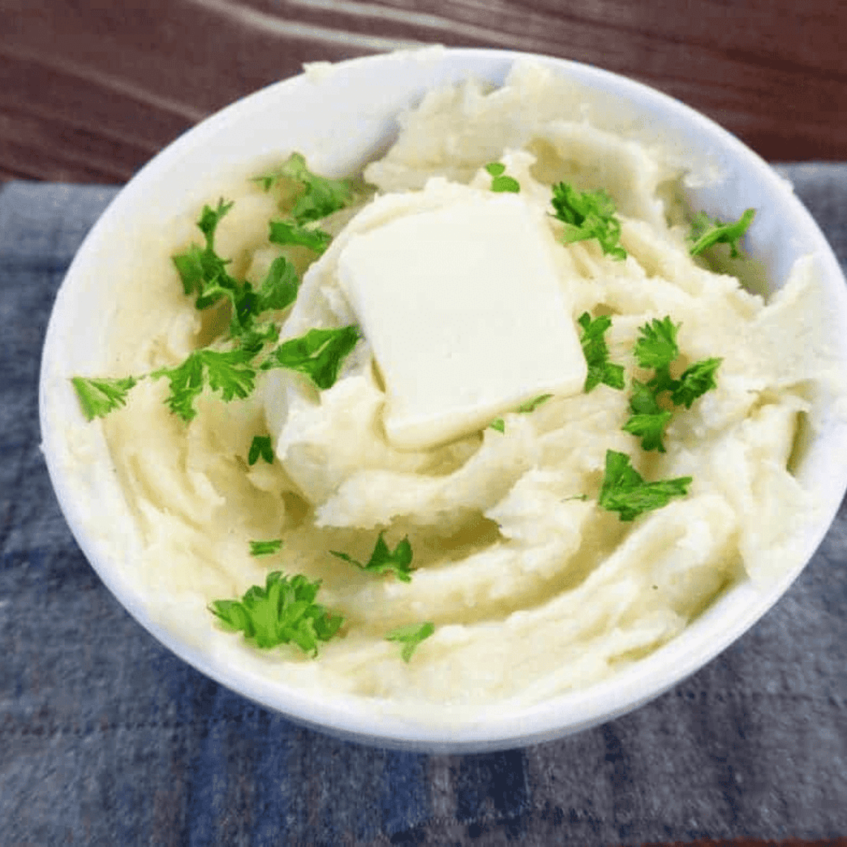 Creamy truffle mashed potatoes garnished with herbs, served next to a meat entree