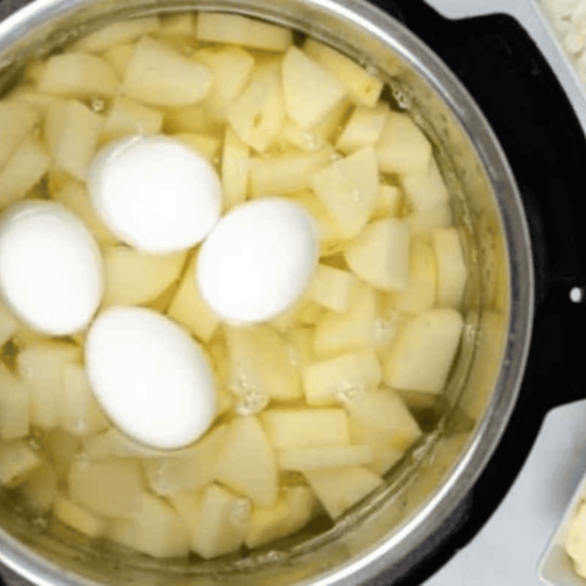 Cubed potatoes and whole eggs in an Instant Pot, covered with water and seasoned with salt, ready for pressure cooking.