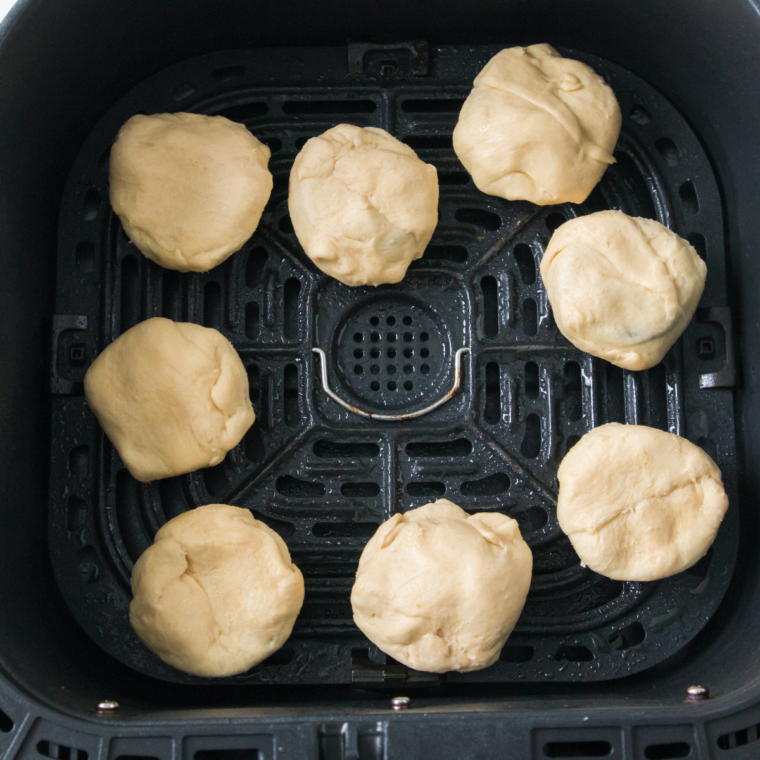 The air fryer is preheated to 350°F and the basket is lined or sprayed to prevent sticking. Preheating helps the dough set quickly once it hits the hot air, locking in the shape.