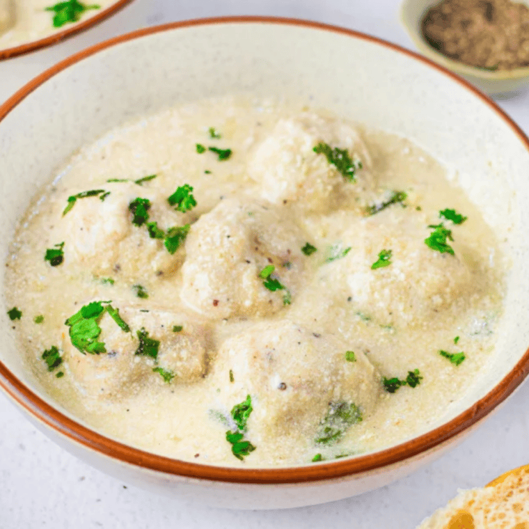 Close-up of cheesy Alfredo meatballs coated in glossy homemade Alfredo sauce