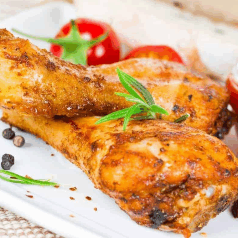 Golden, crispy baked lemon pepper chicken drumsticks served on a plate, garnished with fresh herbs and lemon wedges.