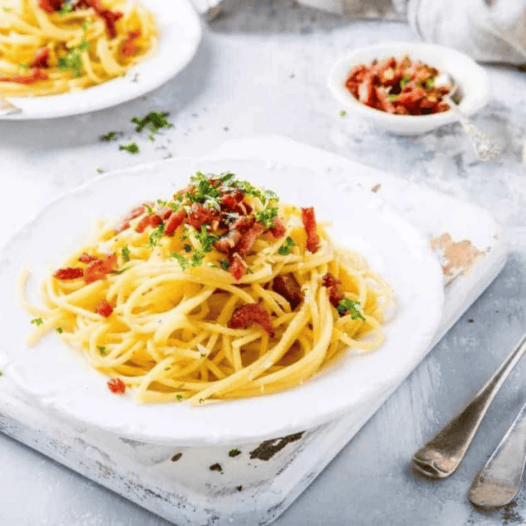 Creamy Instant Pot pasta carbonara with bacon and parmesan in a white bowl.