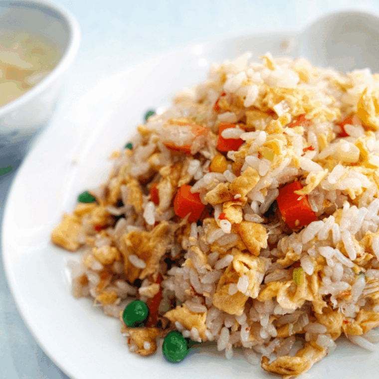 Stirring in peas, carrots, and scrambled eggs into fried rice