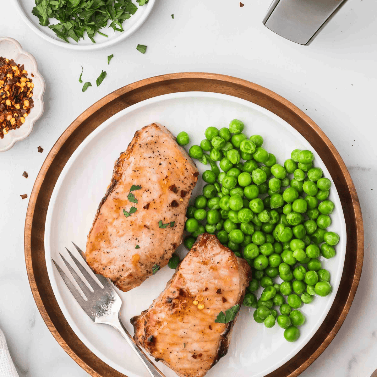 Air fryer frozen pork chops served juicy and golden on a white plate