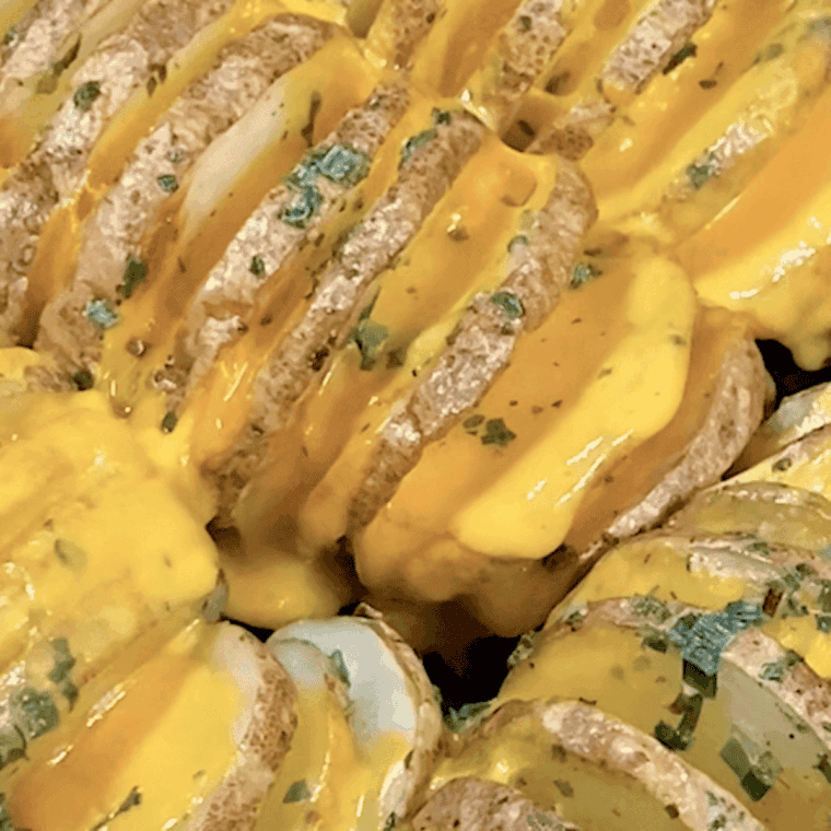 Air frying Hasselback potatoes until cheese melts, then garnishing with fresh herbs and serving hot