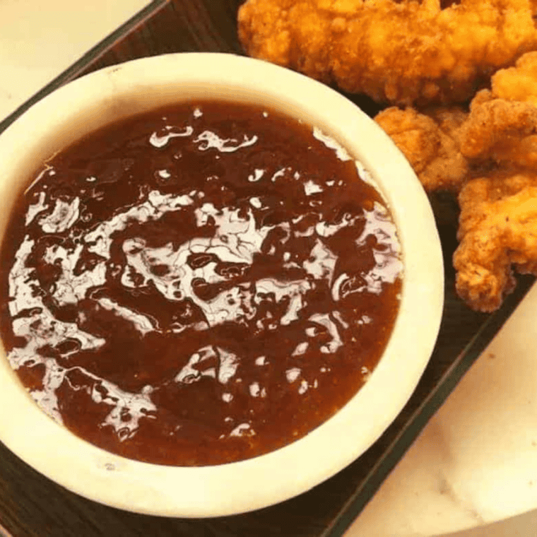 Bowl of bright apricot sweet and sour sauce ready for dipping or drizzling