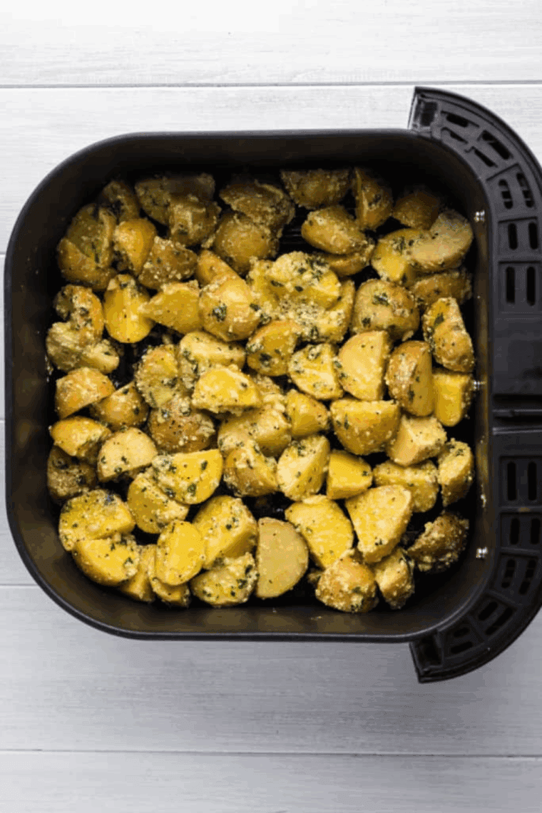Seasoned potatoes arranged in a single layer in the air fryer, cooking until golden, then garnished with chopped parsley