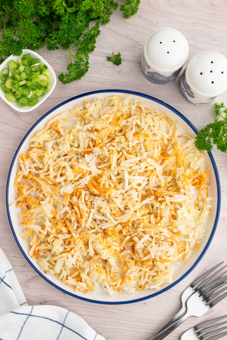 Finished crispy shredded hash browns being seasoned and served hot immediately after air frying for best texture and flavor