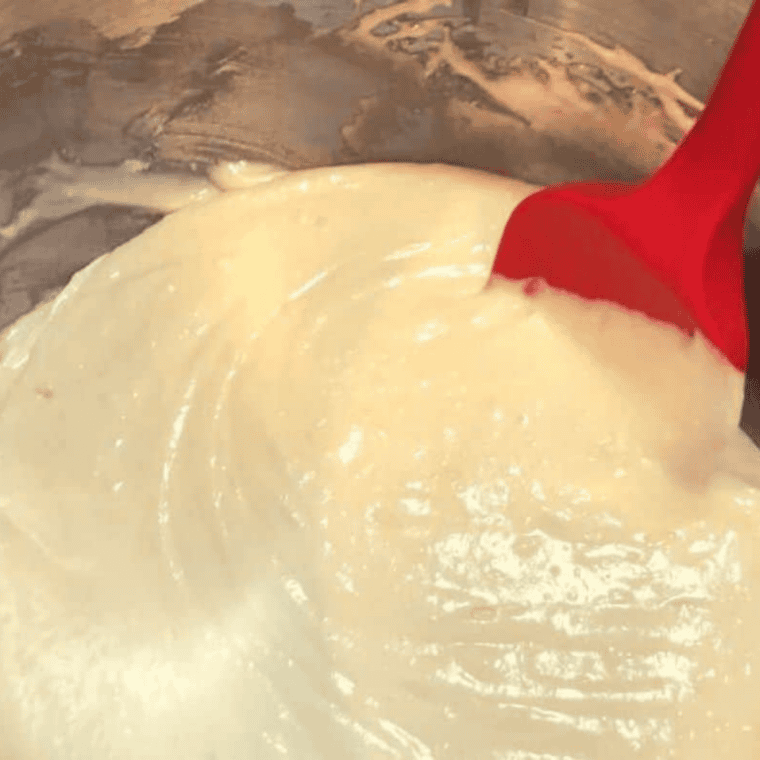 Mix the batter: Yellow cake mix, lemon pudding, 7-Up, eggs, and oil being beaten into smooth batter in a large mixing bowl