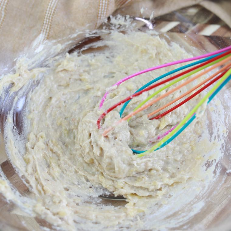 Banana bread mug cake batter spooned into a greased ramekin, filled two-thirds full