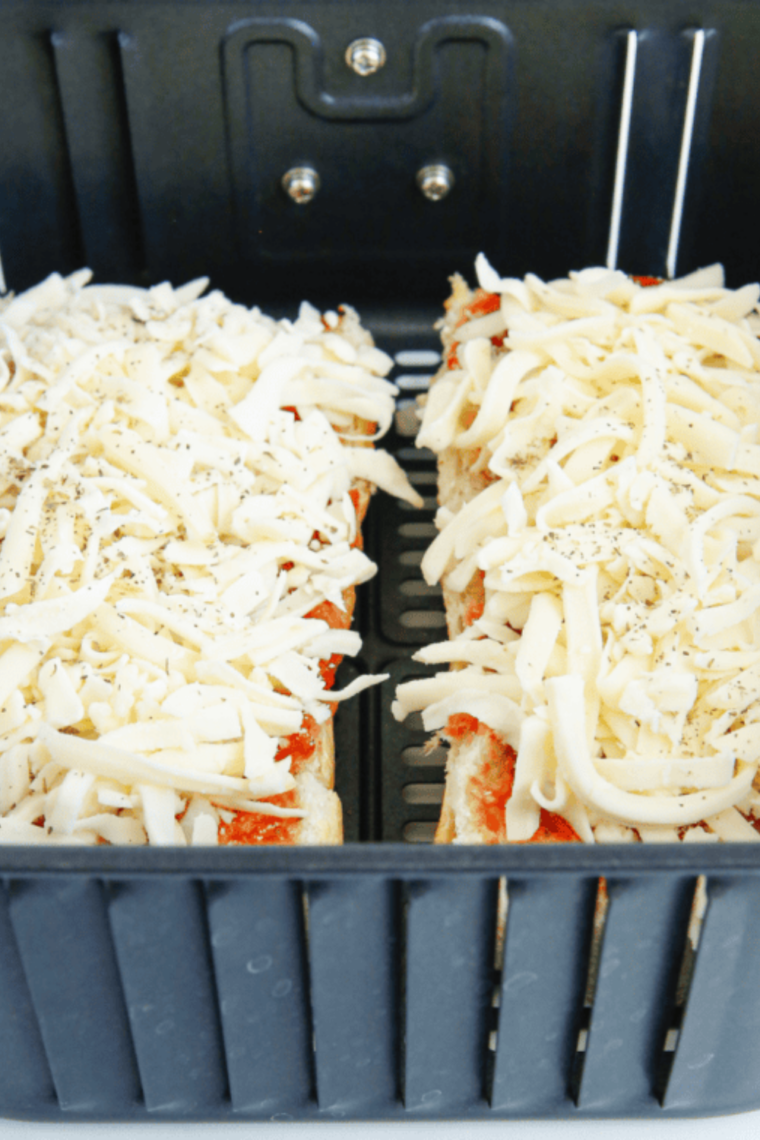 Two French bread pizzas cooking in an air fryer basket at 375°F with melting mozzarella cheese