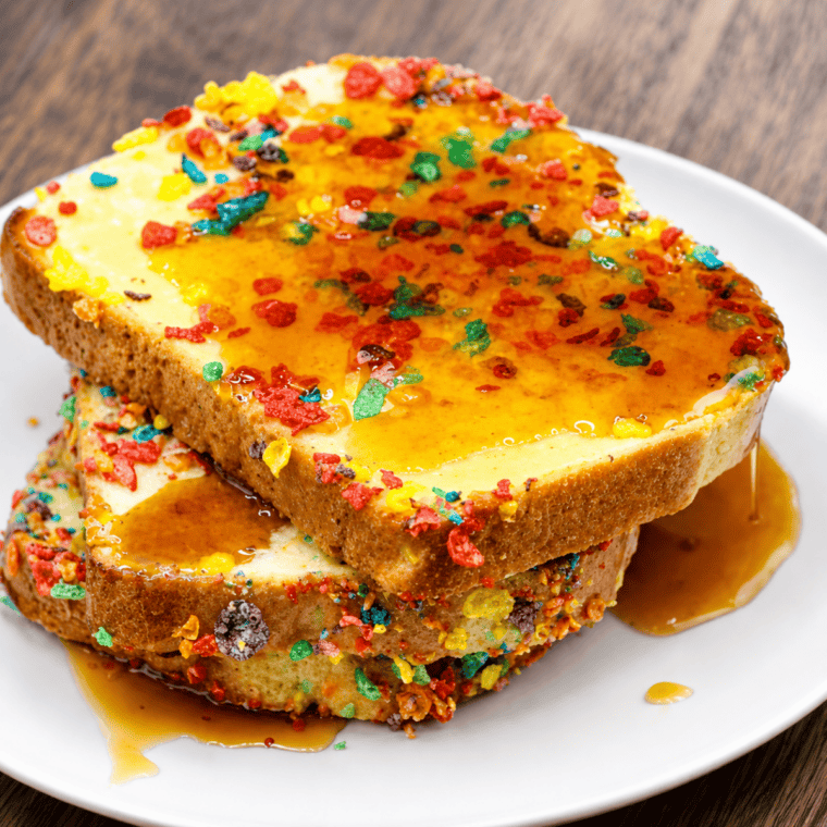 Slices of Air Fryer Fruity Pebbles French Toast topped with whipped cream and colorful cereal crumbs
