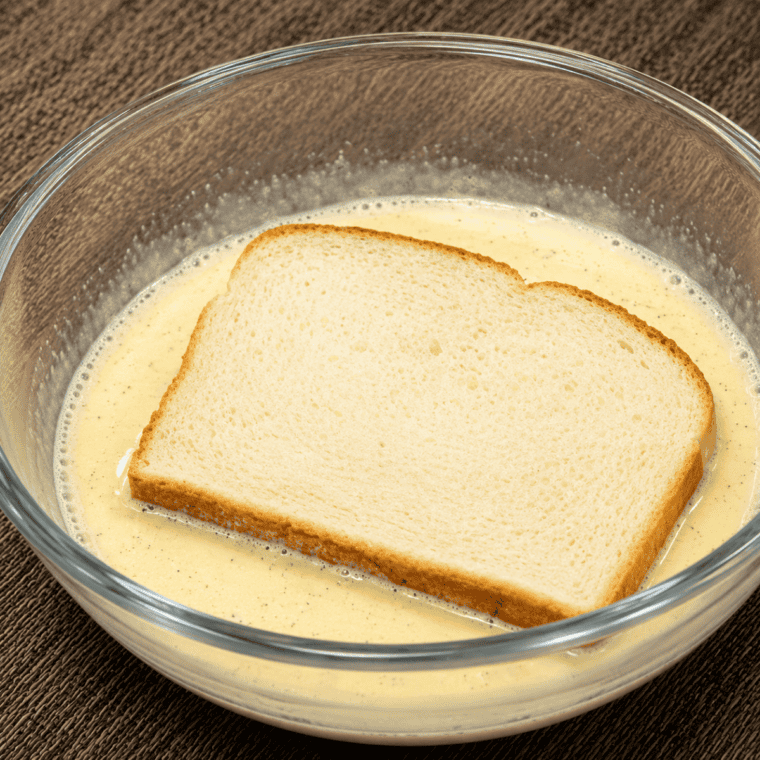 Slice of bread soaking in cinnamon egg custard mixture.