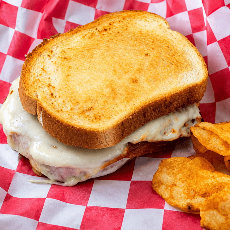 Air fryer Italian grilled cheese sandwich cut in half showing melted provolone, salami and prosciutto