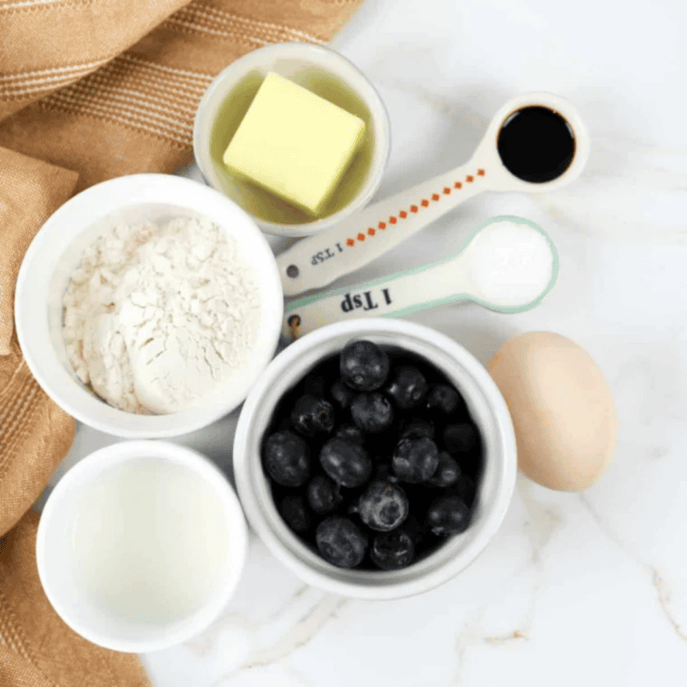 Ingredients for making Air Fryer Pancake Muffins arranged on a table, including pancake mix, eggs, milk, butter, and optional mix-ins.